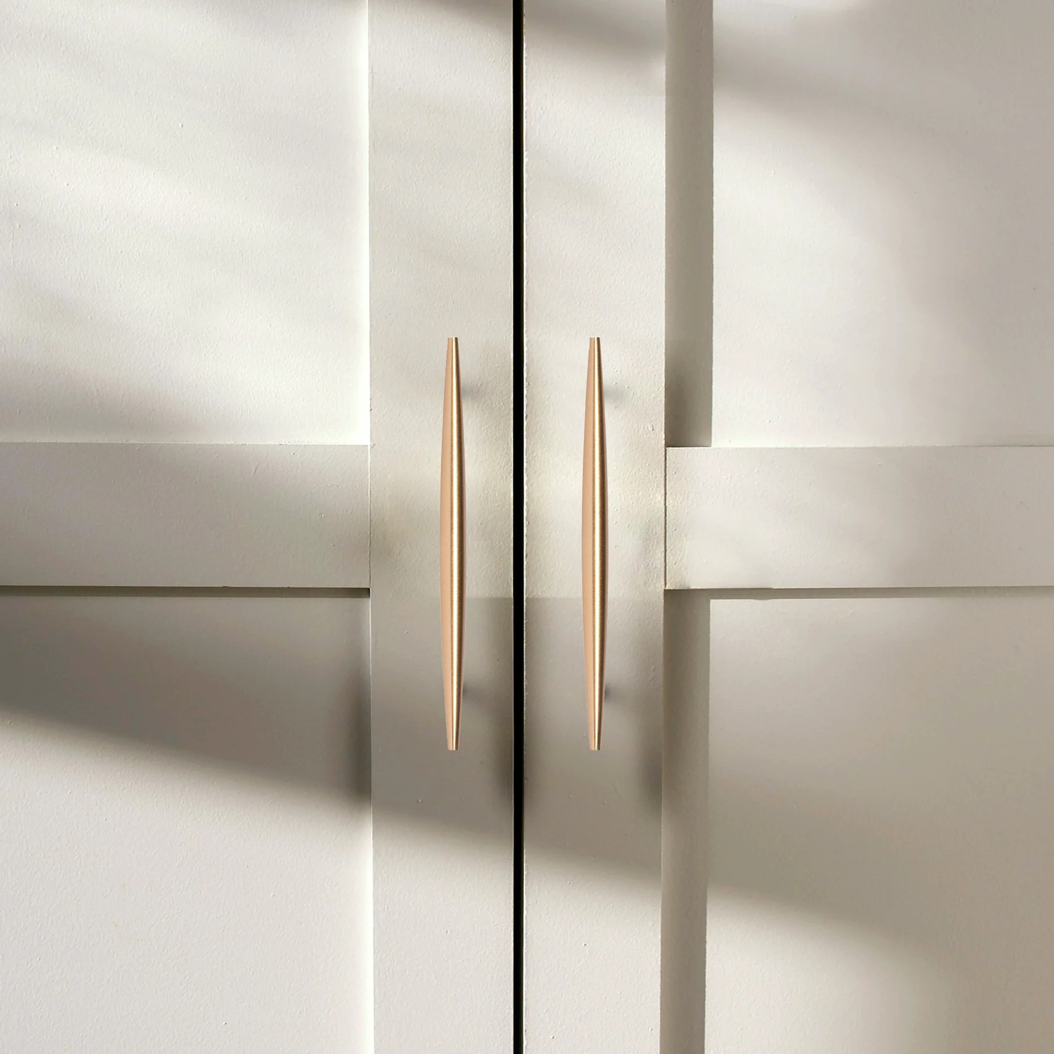 Brass Essence tapered brass spindle cabinet pull with rounded handle and mounting screws for furniture drawers and cabinets.