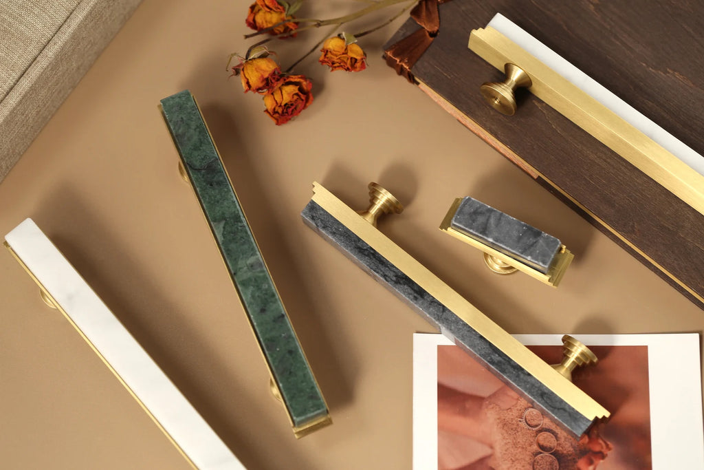 Modern white marble and brass T-bar handle by Brass Essence, showcasing sleek design and polished finish for furniture or cabinetry.
